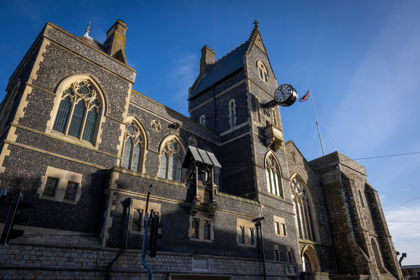 An imposing flint-faced building with arched windows and other detailing.