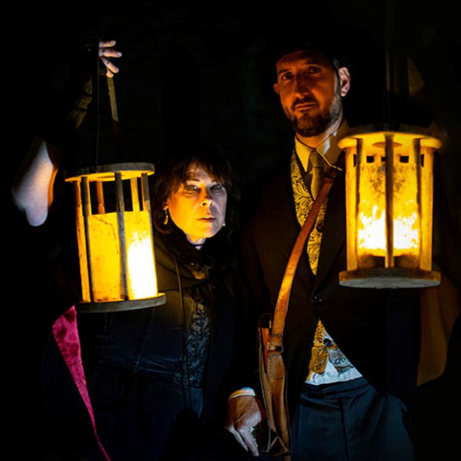 A man and women dressed in Victorian dress carrying lanterns 