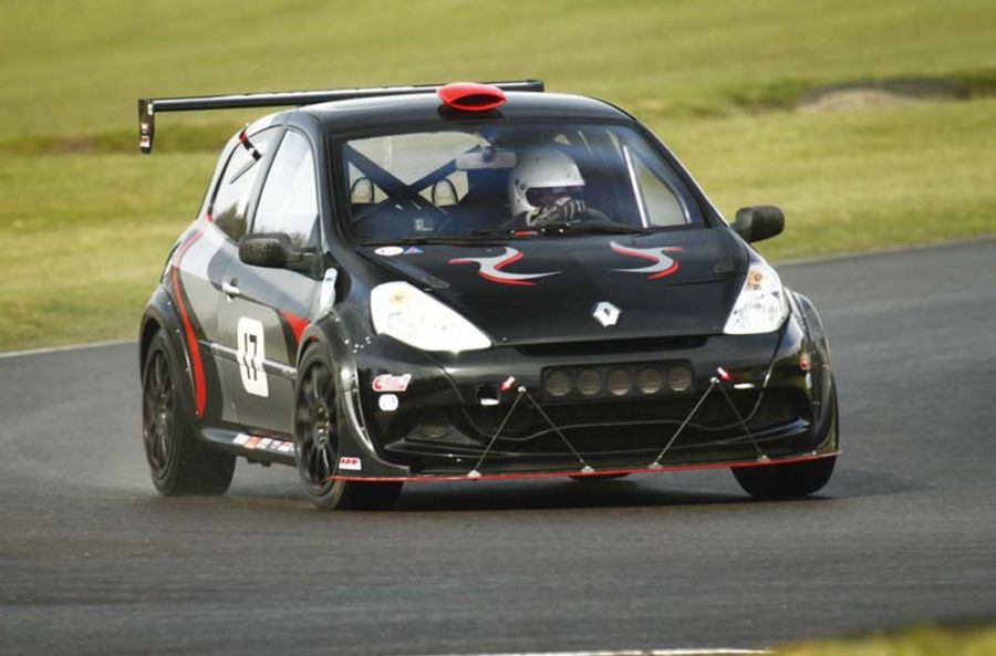 Photo of a black car driven by a racing driver going round a race track