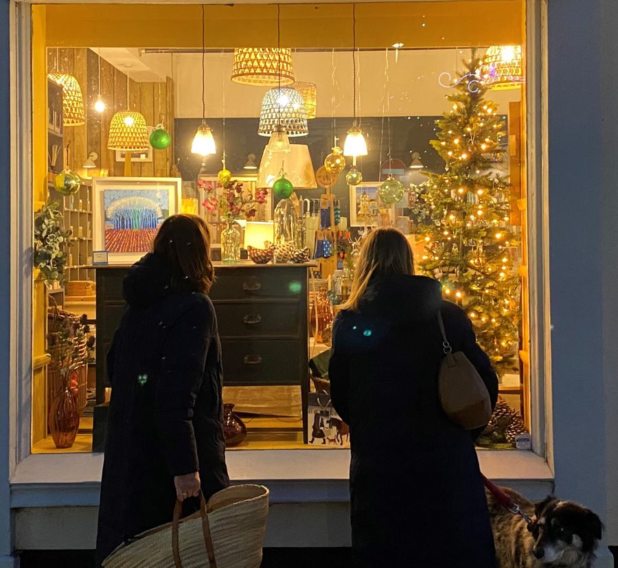 Two women looking into a shop window lit up for Christmas