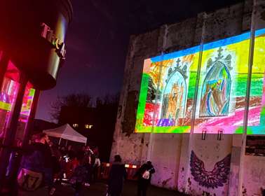 Projection of a colourful drawing onto the side of a building at night