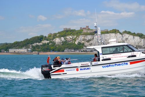 Wetwheels boat with passengers heading out of Dover Harbour with Dover Castle and the white cliffs in the background