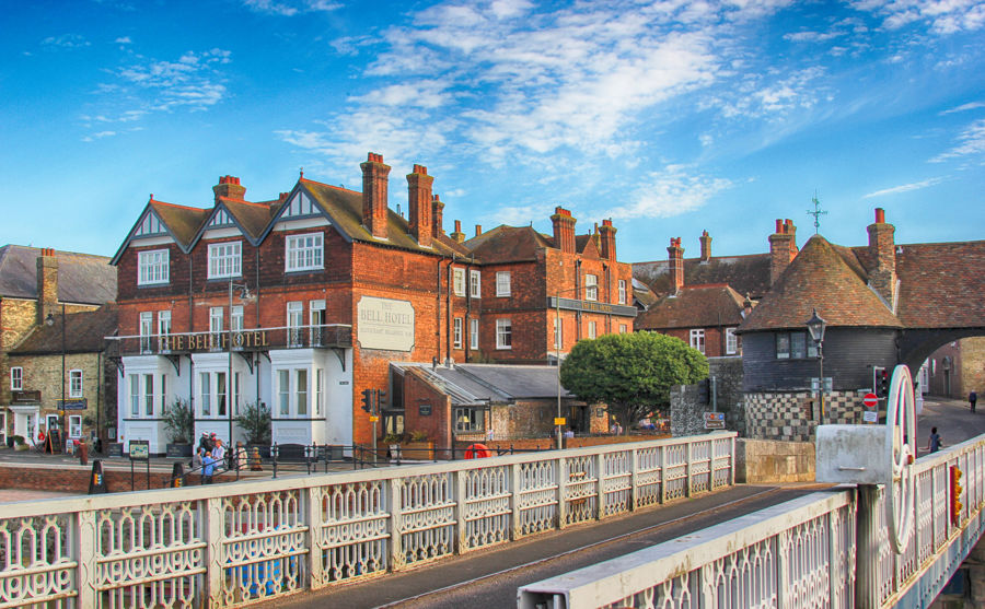 A handsome red-brick building with tall chimneys viewed from the old toll bridge in Sandwich