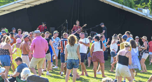 Crowd dancing in front of a band on a stage outdoors