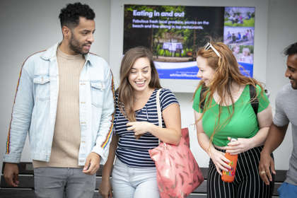 Four people in front of the video display at Deal Pier, laughing and chatting.