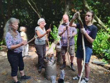 A group of people whittling long staffs