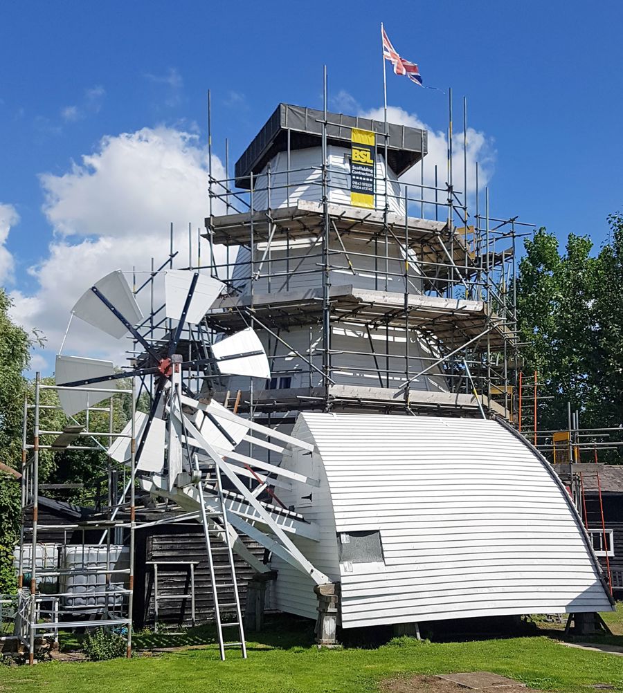 The windmill covered in scaffolding and the cap on the ground beside it.